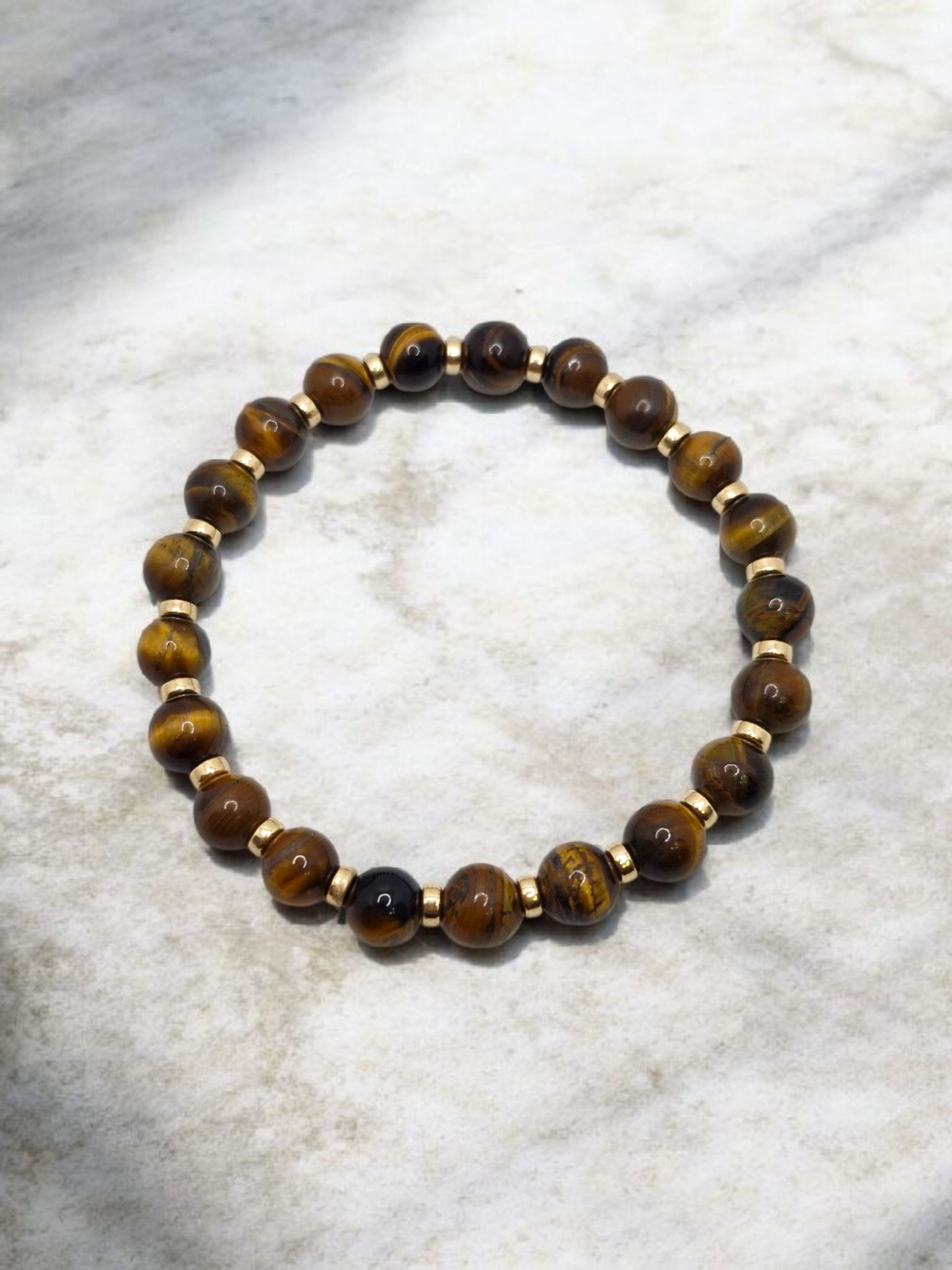 Beaded bracelet with brown and gold beads on a marble surface