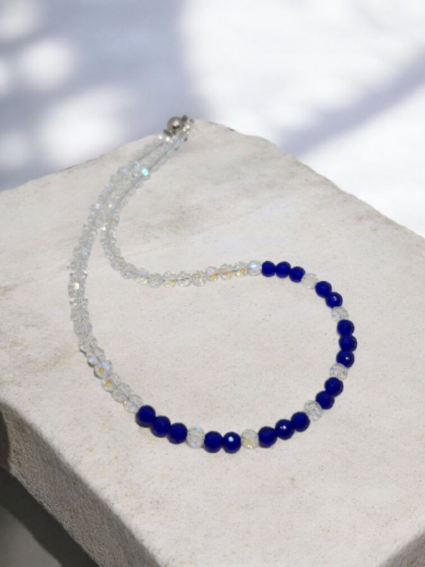Necklace with blue and clear beads on a light gray surface