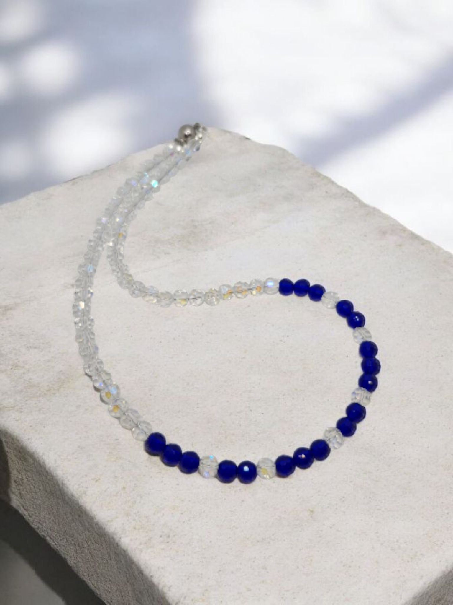Necklace with blue and clear beads on a light gray surface