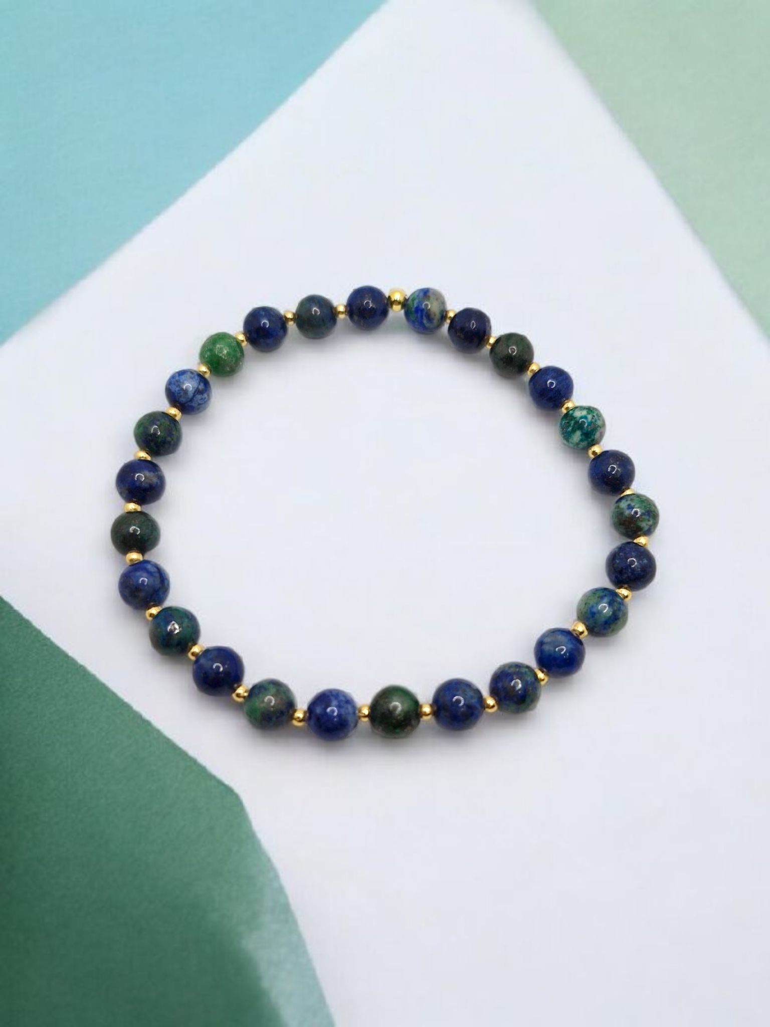 Beaded bracelet with blue and green stones on a white and green background