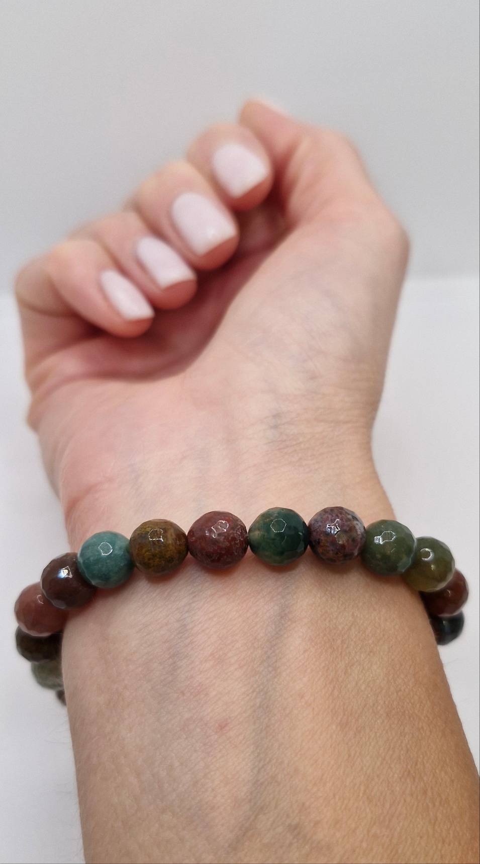 Close-up of Grade AA Indian Agate bracelet, faceted round beads on stretch cord with earthy green and brown hues.