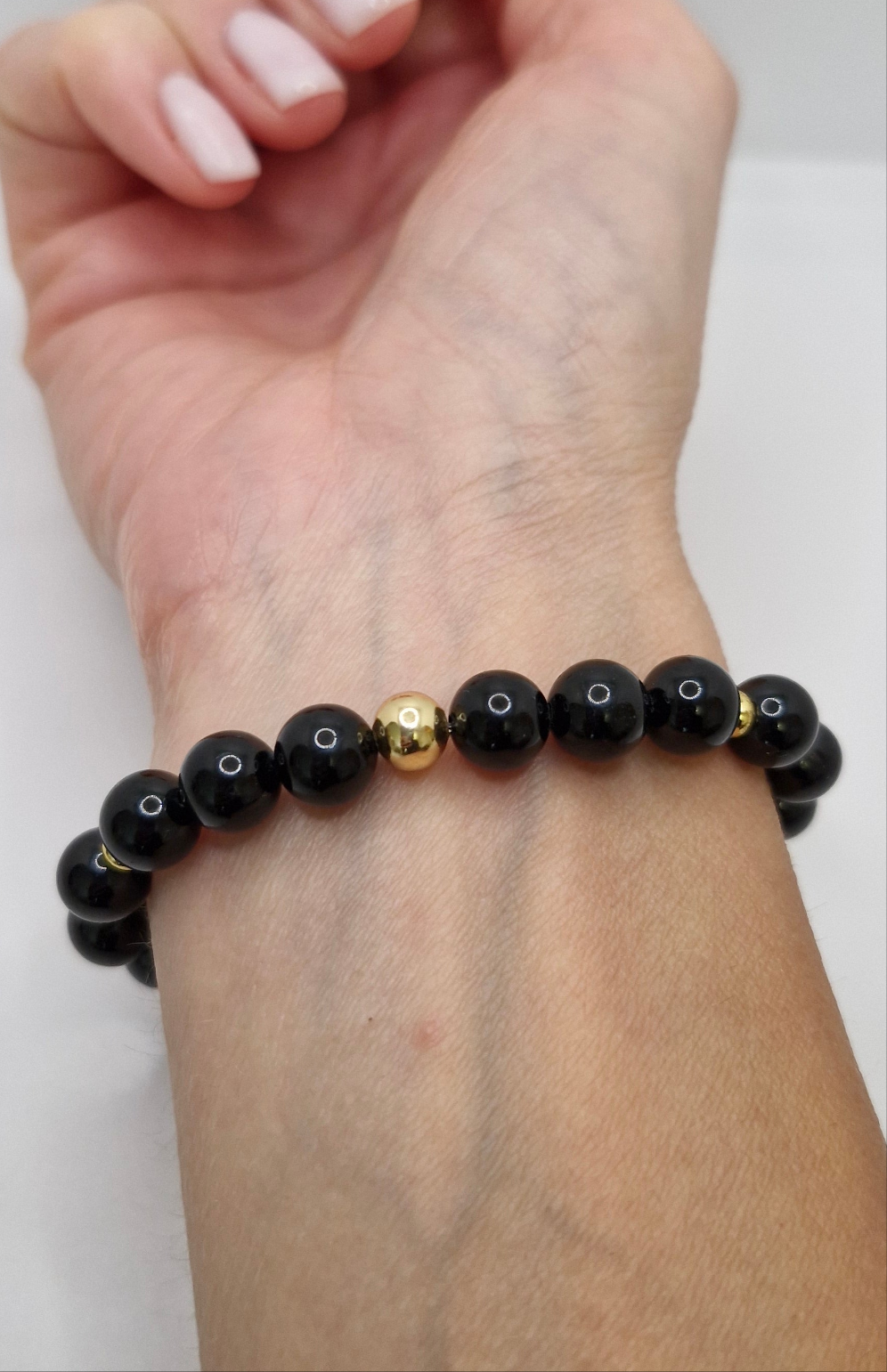 Natural Black Tourmaline stretch bracelet accented with gold-plated disks and a single gold round bead