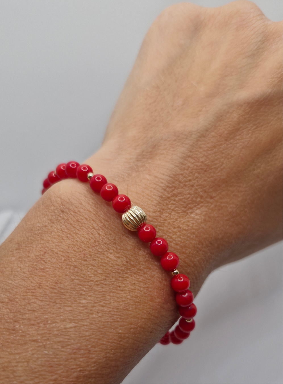 Close-up of handcrafted red Bamboo Coral bracelet featuring smooth 4mm round coral beads and 2mm gold filled beads, showcasing a durable, tarnish-resistant, and elegant design.
