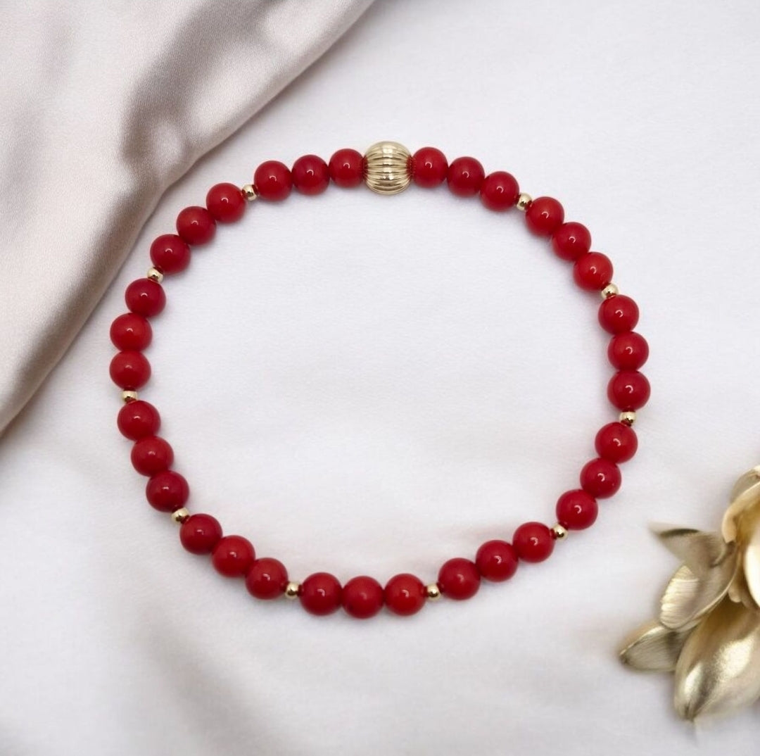Handcrafted stretch bracelet made with 4mm smooth red Bamboo Coral beads and 2mm gold filled accents, combining vibrant color with lasting elegance.